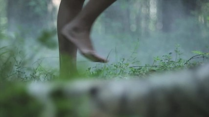 Close up of girl bare feet walking on a green grass in the forest