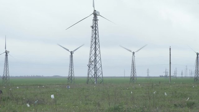 White wind turbines in the green field generating electricity power