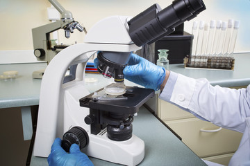 Portrait of caucasian male chemist scientific researcher using microscope in the laboratory interior