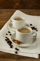 Two coffee cups and brown sugar on the linen napkin, vertical