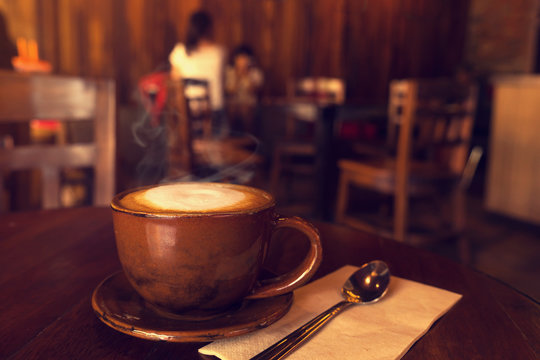 Cup of coffee on table in cafe with people retro instagram effect - shallow depth of field