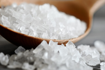 Wooden spoon with salt on a dark background.