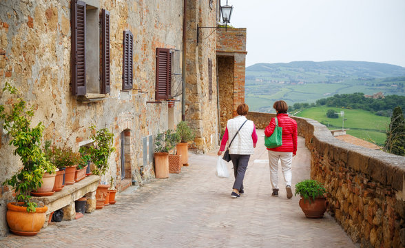 Fototapeta Two senior woman walking along street in medieval city Pienza in Tuscany, Italy.