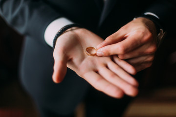 Golden wedding ring on the open palm of groom