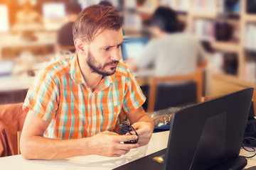 Side view shot of young business hipster man hands busy working on his laptop sitting at  table in a library with vintage filter effect