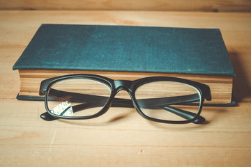 Old books and glasses on a wooden table with filter effect retro