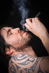 Young man smoking electronic cigarette on black background