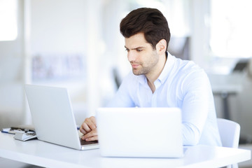 Fototapeta premium Solve the problem. Young businessman working on the solution of the problems on laptop at office