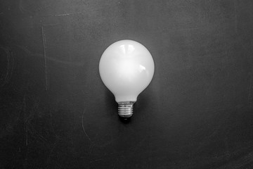 White matte light bulb on the black chalkboard background
