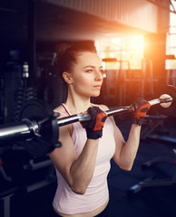 Fototapeta na wymiar Young beautiful woman training biceps with barbell