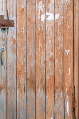 Old wooden door of the vertical boards with the peeled paint