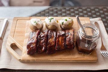 Board of barbecue ribs and potatoe on wooden