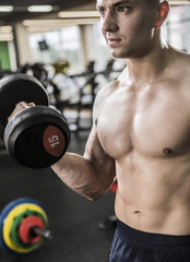 a young man engaged in bodybuilding, the dumbbell raises