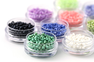 Small colorful beads on transparent round boxes on white background