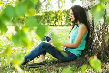 Beautiful woman relaxing outdoors on grass about tree