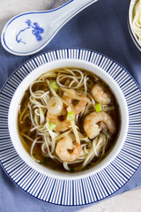 Chinese soup with prawns, beige background, white and blue plates.