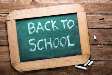Fototapeta premium blackboard with chalk and written text back to school on wooden