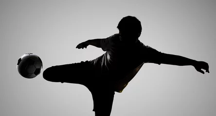 Foto auf Acrylglas silhouette football player kicking the ball © phonlamaiphoto