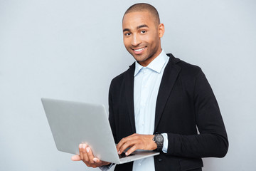 Happy african american young man holding and using laptop