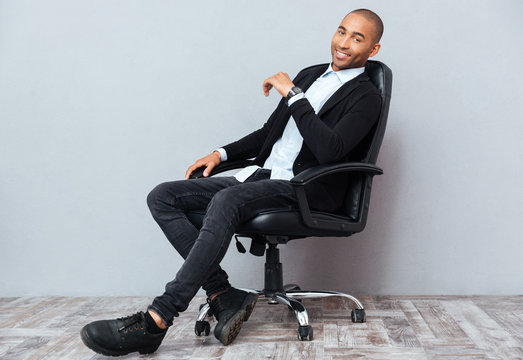 Happy african american young man sitting in leather office chair