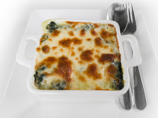 Baked spinach and cheese with spoon and fork on the white backgr