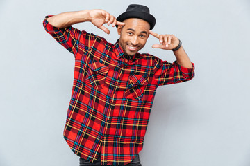 Smiling african young man standing and pointing on his head