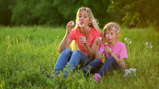 Mother and the child blowing bubbles. Slow motion
