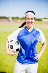 Happy soccer player standing with a ball