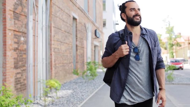 man with backpack walking along city street 18
