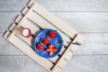 Strawberry breakfast on a blue plate and milk flat lay