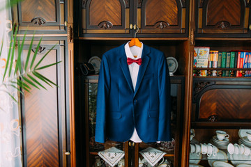 Excellent expensive blue suit hanging on wardrobe in window light at luxury interior of hotel room