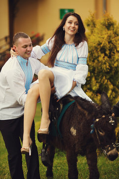 A picture of a pretty brunette sitting on the donkey and a man i
