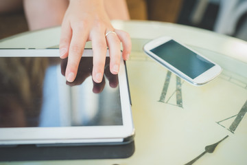 Close up on the hand of a young handsome caucasian girl using technological devices like tablet and smartphone - mutitasking, technology concept
