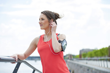 Fit woman jogger resting after run listening music.