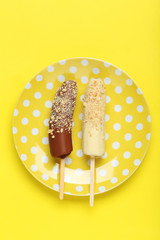Banana covered in chocolate on a yellow background