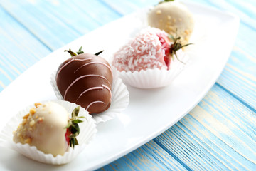 Strawberries covered in chocolate on a blue wooden table