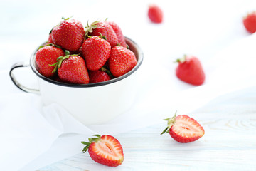Strawberries in cup on white wooden table