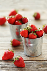 Fresh and tasty strawberries in bucket on a grey wooden table