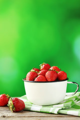 Fresh and tasty strawberries in cup on a grey wooden table