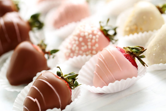 Strawberries covered in chocolate on a white wooden table