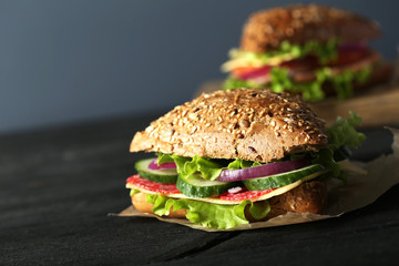 Tasty sandwiches with salami on a black wooden background