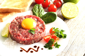 Beef tartare with egg yolk on a grey wooden table