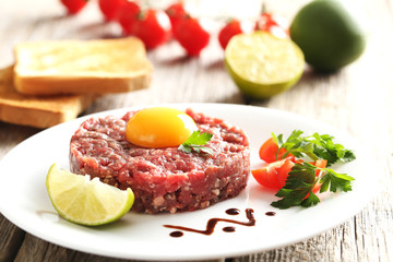 Beef tartare with egg yolk on a grey wooden table