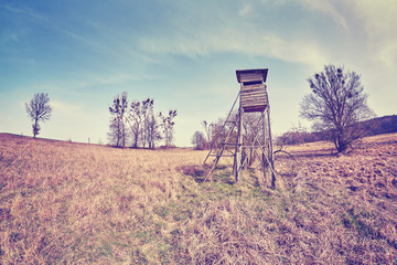 Vintage toned fisheye lens photo of a hunting pulpit on a field, Poland.