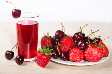 Juice in a glass of fresh red strawberries and cherries