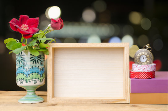 Photo frame with books and flowers on the wooden table