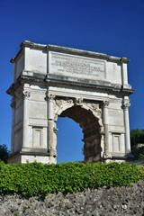 Fototapeta na wymiar Arch of Titus. Ancient triumphal arch dedicated to Emperor Titus, at the entrance of the Roman Forum, behind a ruined wall (1st century A.D.), 