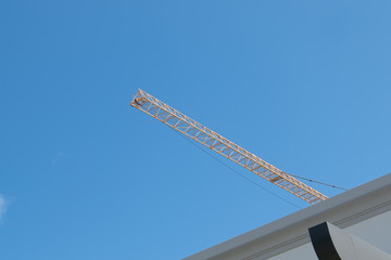 nice color combination of yellow high long crane arrow at construction site and clear light blue sky day. 