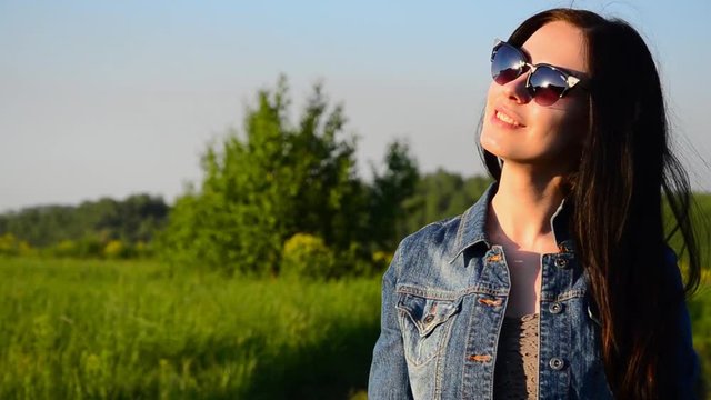 brunette wears glasses outdoors. brunette wears sunglasses outdoors and smiling. girl in glasses smiling and looking at the sunset
