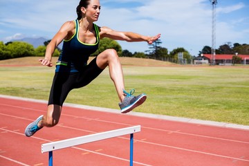Obraz premium Female athlete jumping above the hurdle